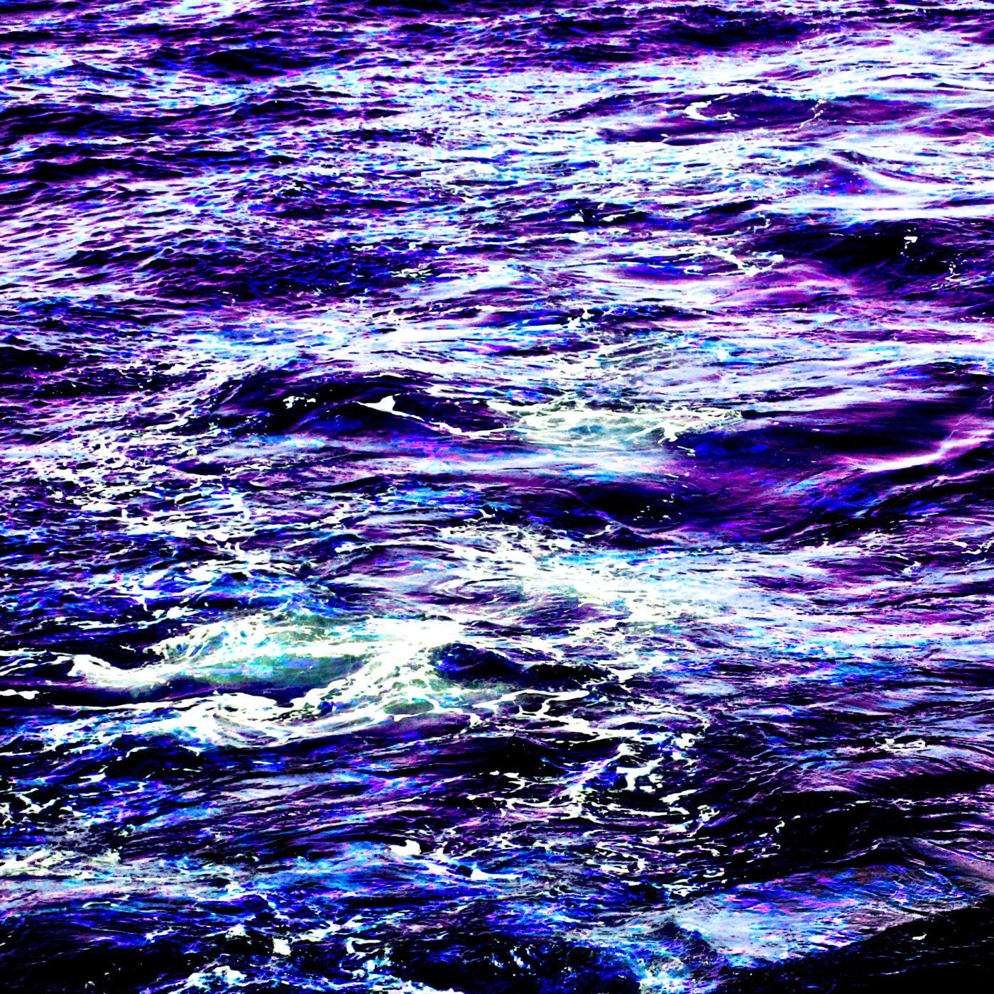 The surface of an ocean, with many waves visible. The water is a combination of deep blues and purples.