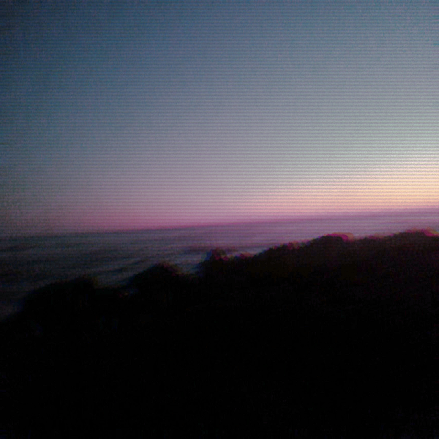 Tilted view from a coastline as the sun sets off-screen. Rock faces are darkened and the image has scanlines.
